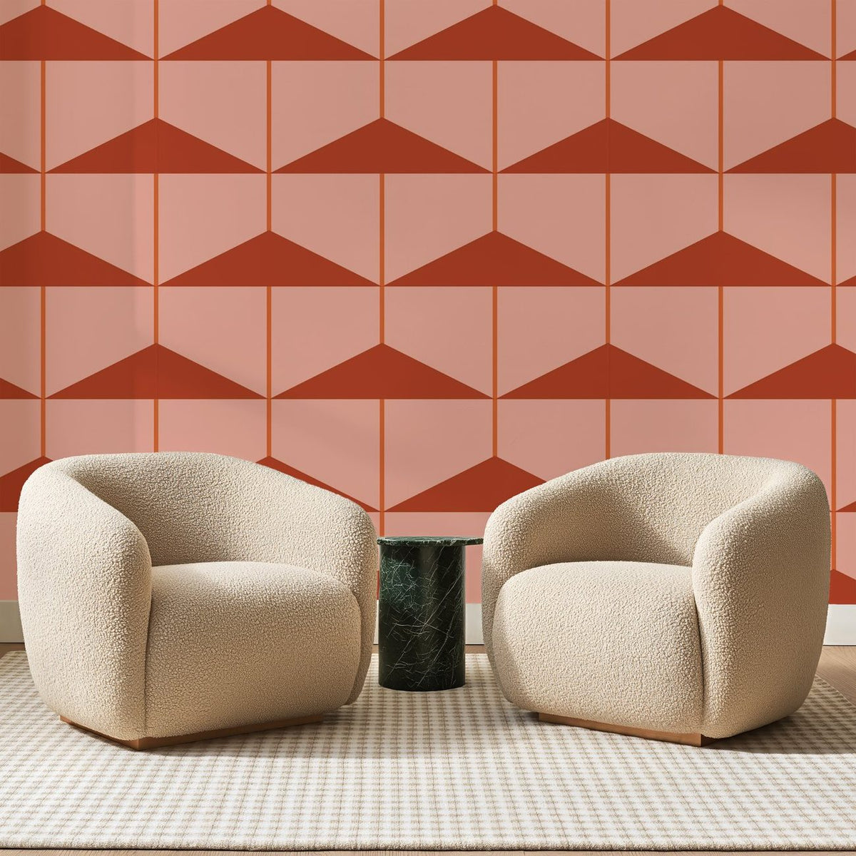 Papier peint panoramique Triangles Étagés Rose Pêche, posé sur toute la paroi d'un salon, derrière deux fauteuils en bouclette crème et un guéridon en marbre vert