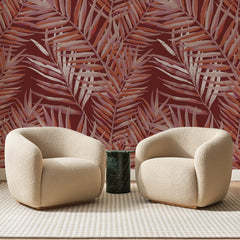 Papier peint panoramique Palmes Rosées sur Fond Brique, posé sur toute la paroi d'un salon, derrière deux fauteuils en bouclette crème et un guéridon en marbre vert