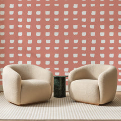 Papier peint panoramique Carreaux Peints Corail, posé sur toute la paroi d'un salon, derrière deux fauteuils en bouclette crème et un guéridon en marbre vert
