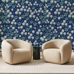 Papier peint panoramique Marguerites sur Bleu Marine, posé sur toute la paroi d'un salon, derrière deux fauteuils en bouclette crème et un guéridon en marbre vert