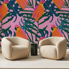 Papier peint panoramique Perroquets Orange sur Rose Vif, posé sur toute la paroi d'un salon, derrière deux fauteuils en bouclette crème et un guéridon en marbre vert