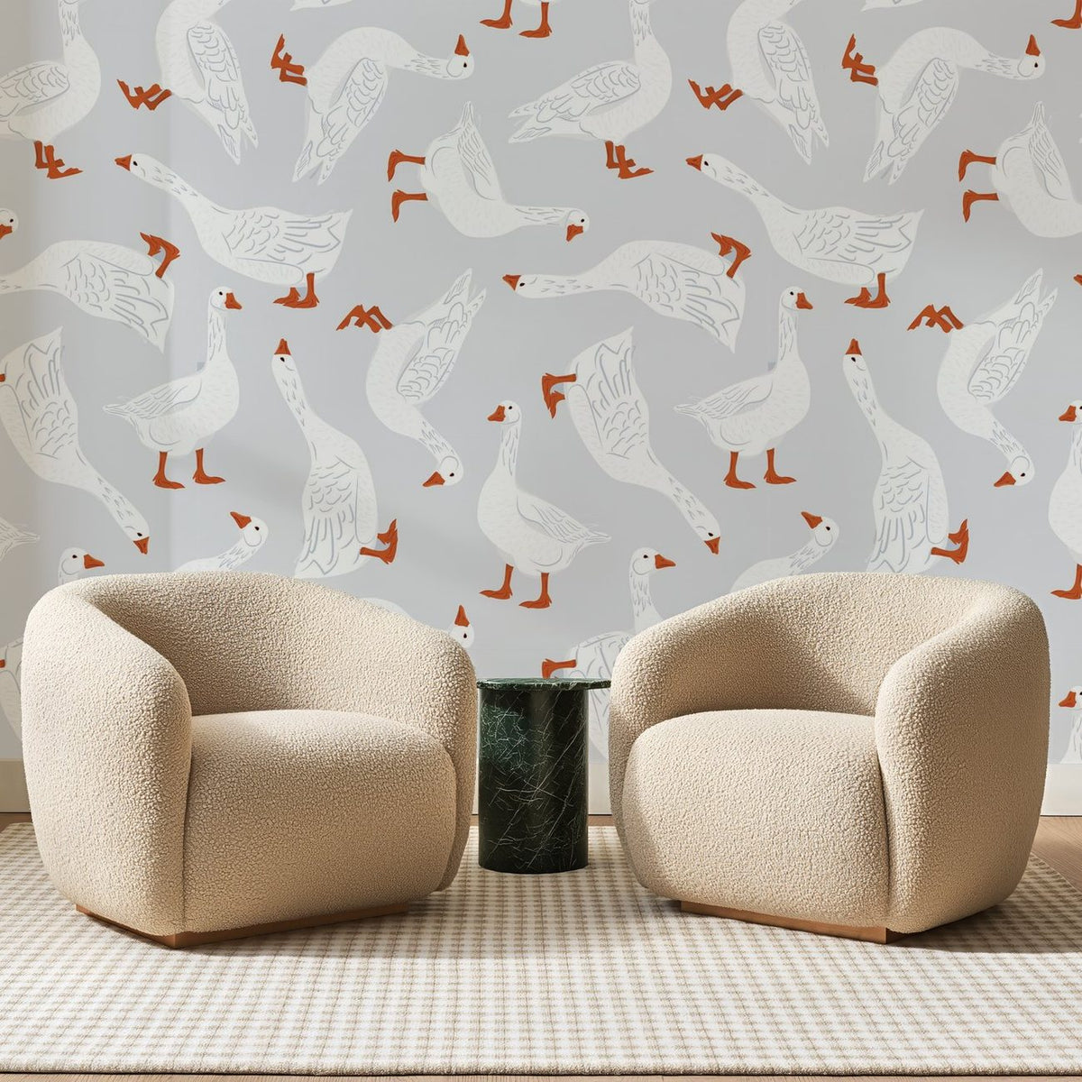 Papier peint panoramique Troupeau d'Oies Gris Perle, posé sur toute la paroi d'un salon, derrière deux fauteuils en bouclette crème et un guéridon en marbre vert