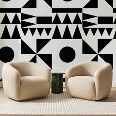 Papier peint panoramique Géométrie Noire sur Blanc, posé sur toute la paroi d'un salon, derrière deux fauteuils en bouclette crème et un guéridon en marbre vert