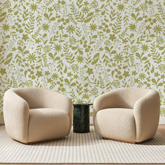 Papier peint panoramique Semis Fleuri Vert Olive, posé sur toute la paroi d'un salon, derrière deux fauteuils en bouclette crème et un guéridon en marbre vert