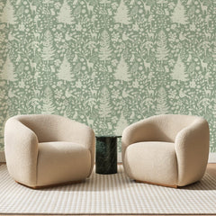 Papier peint panoramique Forêt aux Cerfs Sauge, posé sur toute la paroi d'un salon, derrière deux fauteuils en bouclette crème et un guéridon en marbre vert
