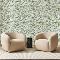 Papier peint panoramique Feuillage de Saule Vert Sauge, posé sur toute la paroi d'un salon, derrière deux fauteuils en bouclette crème et un guéridon en marbre vert