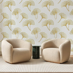 Papier peint panoramique Feuilles de Ginkgo Dorées, posé sur toute la paroi d'un salon, derrière deux fauteuils en bouclette crème et un guéridon en marbre vert