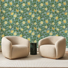 Papier peint panoramique Citrons sur Vert d'Eau, posé sur toute la paroi d'un salon, derrière deux fauteuils en bouclette crème et un guéridon en marbre vert