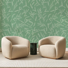 Papier peint panoramique Branchages Blancs sur Sauge, posé sur toute la paroi d'un salon, derrière deux fauteuils en bouclette crème et un guéridon en marbre vert