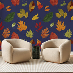 Papier peint panoramique Feuillage d'Automne Bleu Nuit, posé sur toute la paroi d'un salon, derrière deux fauteuils en bouclette crème et un guéridon en marbre vert