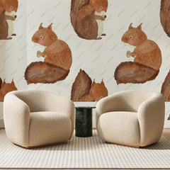 Papier peint panoramique Écureuils Roux de la Forêt, posé sur toute la paroi d'un salon, derrière deux fauteuils en bouclette crème et un guéridon en marbre vert