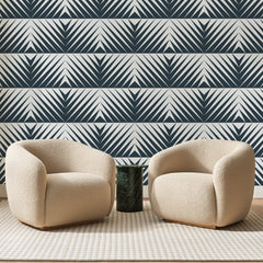 Papier peint panoramique Chevrons Rayés Bleu Ardoise, posé sur toute la paroi d'un salon, derrière deux fauteuils en bouclette crème et un guéridon en marbre vert