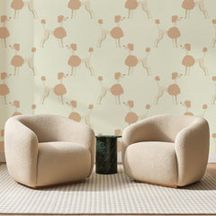 Papier peint panoramique Caniches Rose Poudré, posé sur toute la paroi d'un salon, derrière deux fauteuils en bouclette crème et un guéridon en marbre vert