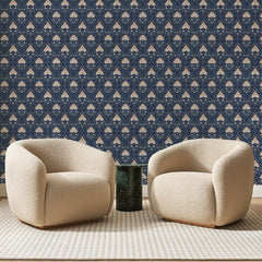 Papier peint panoramique Damas de Protéas Bleu Nuit, posé sur toute la paroi d'un salon, derrière deux fauteuils en bouclette crème et un guéridon en marbre vert