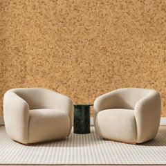 Papier peint panoramique Grain de Liège Miel, posé sur toute la paroi d'un salon, derrière deux fauteuils en bouclette crème et un guéridon en marbre vert