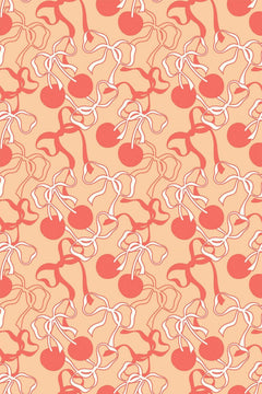 Le décor à plat : des nœuds de ruban blancs et corail et des cerises corail sur un fond pêche clair.