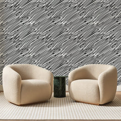 Papier peint panoramique Griffonnages Noirs en Diagonale, posé sur toute la paroi d'un salon, derrière deux fauteuils en bouclette crème et un guéridon en marbre vert
