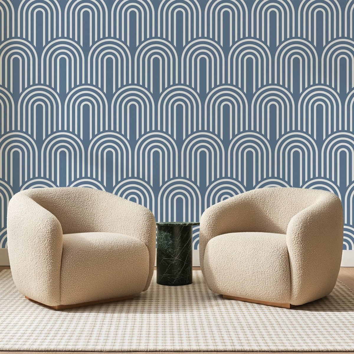 Papier peint panoramique Arcades Nervurées Bleu de Chine, posé sur toute la paroi d'un salon, derrière deux fauteuils en bouclette crème et un guéridon en marbre vert
