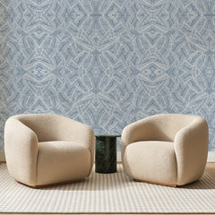 Papier peint panoramique Palmes Hachurées Bleu Porcelaine, posé sur toute la paroi d'un salon, derrière deux fauteuils en bouclette crème et un guéridon en marbre vert