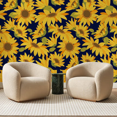 Papier peint panoramique Tournesols sur Bleu Nuit, posé sur toute la paroi d'un salon, derrière deux fauteuils en bouclette crème et un guéridon en marbre vert