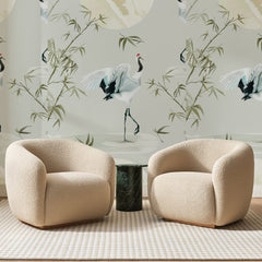 Papier peint panoramique Grues et Bambous Vert Pâle, posé sur toute la paroi d'un salon, derrière deux fauteuils en bouclette crème et un guéridon en marbre vert