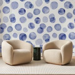 Papier peint panoramique Pois à l'Aquarelle Indigo, posé sur toute la paroi d'un salon, derrière deux fauteuils en bouclette crème et un guéridon en marbre vert