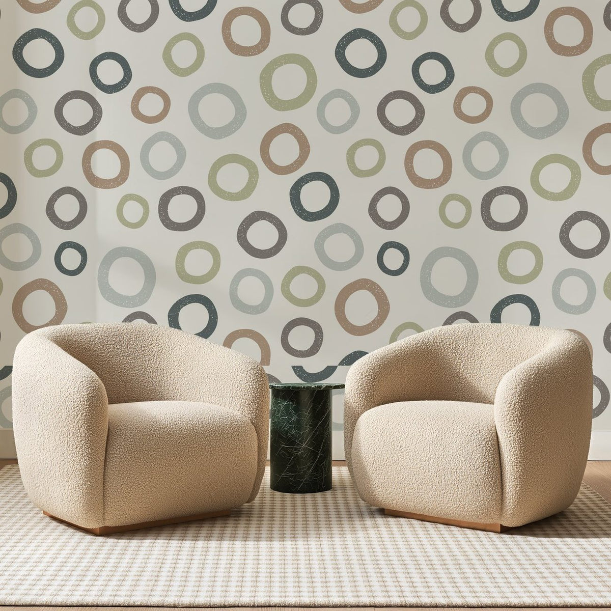 Papier peint panoramique Anneaux Tamponnés sur Crème, posé sur toute la paroi d'un salon, derrière deux fauteuils en bouclette crème et un guéridon en marbre vert