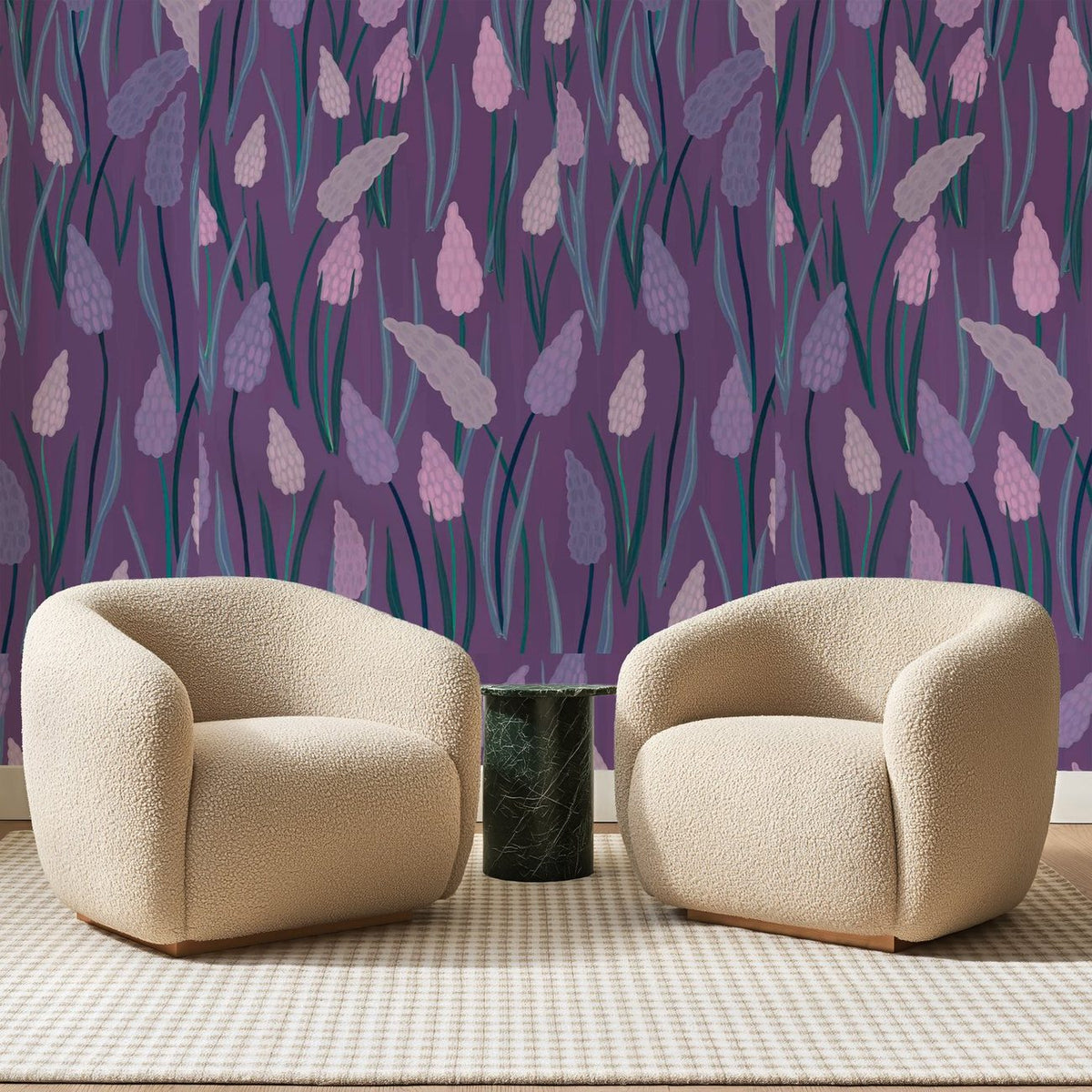 Papier peint panoramique Muscaris Mauves sur Prune, posé sur toute la paroi d'un salon, derrière deux fauteuils en bouclette crème et un guéridon en marbre vert