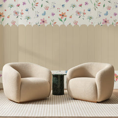 Papier peint panoramique Palissade Fleurie Sable, posé sur toute la paroi d'un salon, derrière deux fauteuils en bouclette crème et un guéridon en marbre vert