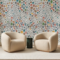 Papier peint panoramique Galets Colorés sur Crème, posé sur toute la paroi d'un salon, derrière deux fauteuils en bouclette crème et un guéridon en marbre vert
