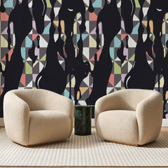 Papier peint panoramique Coulures Noires sur Triangles Pastel, posé sur toute la paroi d'un salon, derrière deux fauteuils en bouclette crème et un guéridon en marbre vert
