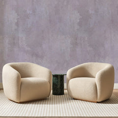 Papier peint panoramique Enduit Rose Poudré, posé sur toute la paroi d'un salon, derrière deux fauteuils en bouclette crème et un guéridon en marbre vert
