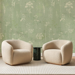 Papier peint panoramique Herbier Ivoire sur Vert Amande, posé sur toute la paroi d'un salon, derrière deux fauteuils en bouclette crème et un guéridon en marbre vert