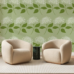 Papier peint panoramique Ombelles Blanches Vert Amande, posé sur toute la paroi d'un salon, derrière deux fauteuils en bouclette crème et un guéridon en marbre vert