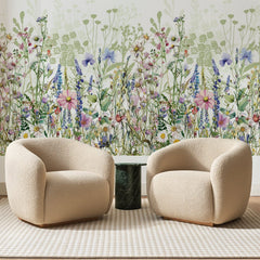 Papier peint panoramique Prairie Aquarelle Rose et Bleu, posé sur toute la paroi d'un salon, derrière deux fauteuils en bouclette crème et un guéridon en marbre vert