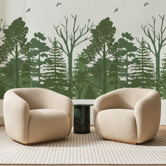 Papier peint panoramique Lisière de Forêt Sauge, posé sur toute la paroi d'un salon, derrière deux fauteuils en bouclette crème et un guéridon en marbre vert
