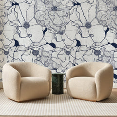 Papier peint panoramique Fleurs au Trait Bleu Marine, posé sur toute la paroi d'un salon, derrière deux fauteuils en bouclette crème et un guéridon en marbre vert