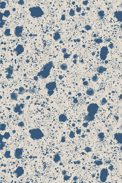 Le décor à plat : taches et fines gouttes bleu encre projetées sur un fond écru grisé.