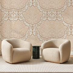 Papier peint panoramique Damas Feuilles Ivoire et Ocre, posé sur toute la paroi d'un salon, derrière deux fauteuils en bouclette crème et un guéridon en marbre vert